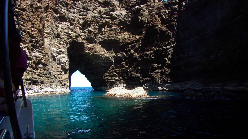 Boat below the high sea cliffs on a Na Pali Coast boat tour from Kikiaola Harbor, Kauai