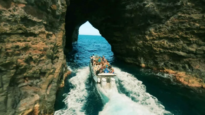 Inflatable raft passing a sea cave on a Na Pali Coast boat tour from Waimea, Kauai