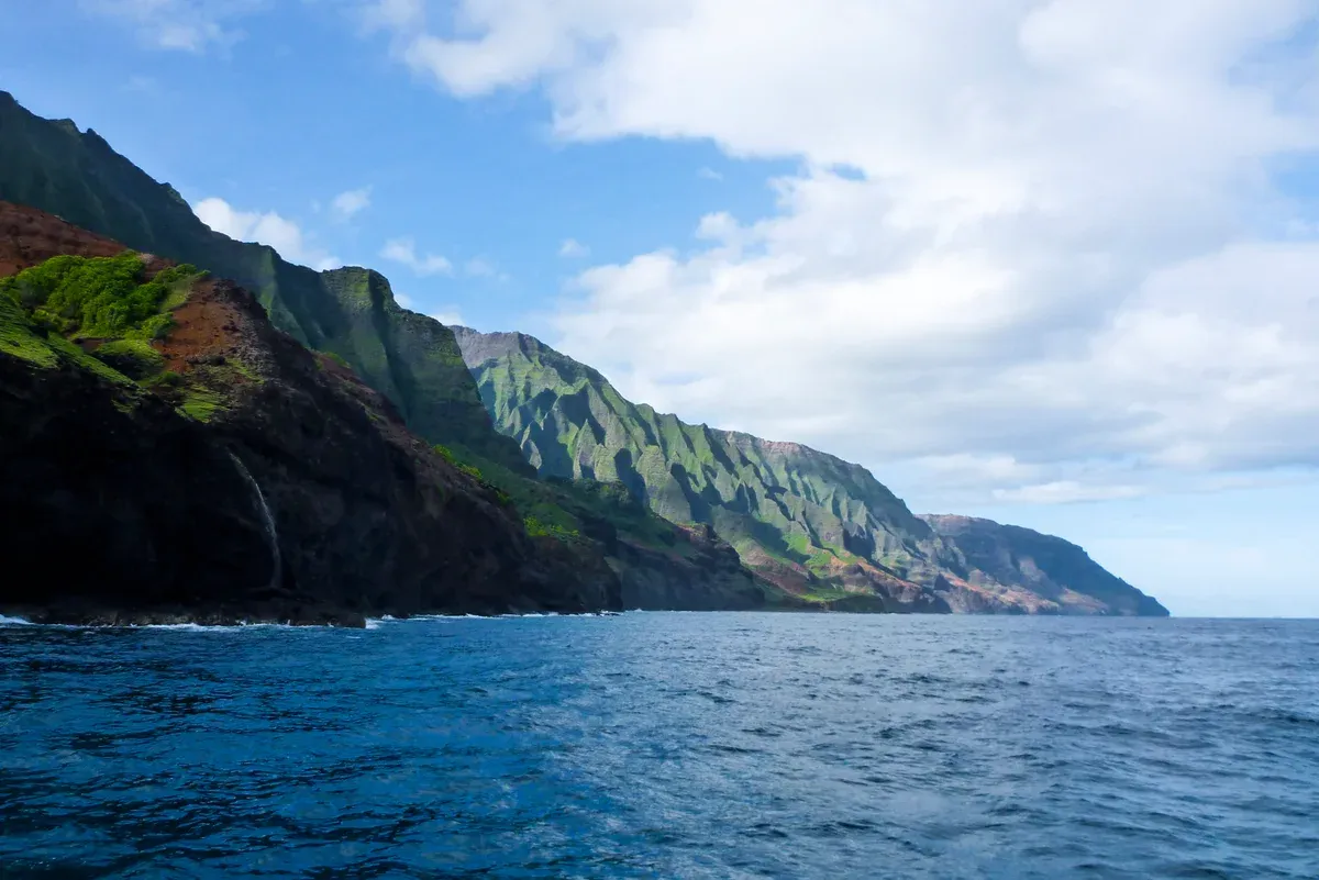 Green fluted sea cliffs of the Na Pali Coast seen from the water on Kauai Napali Coast boat tours