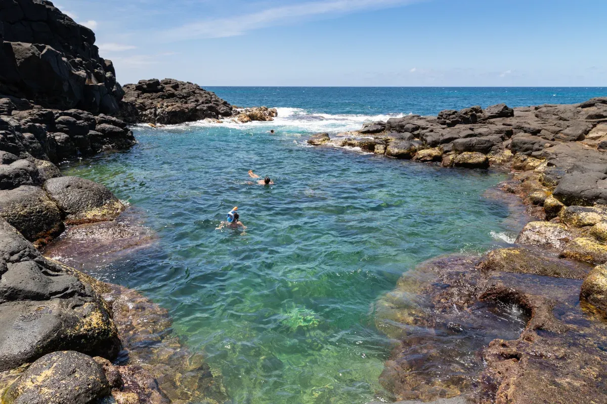 Snorkeler in a clear lava-rock tide pool at Princeville on Kauai, similar to Na Pali Coast snorkel tours