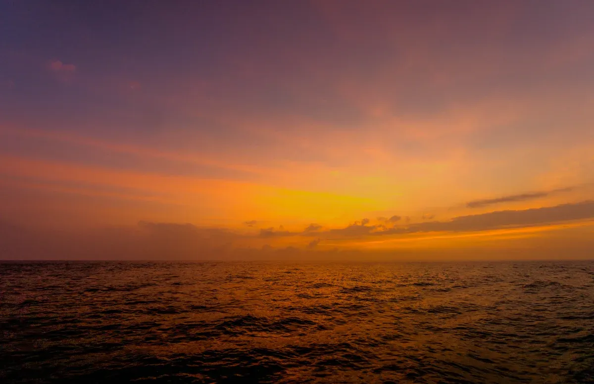 Orange sunset over the sea off the Na Pali Coast on a Kauai Napali Coast sunset dinner cruise